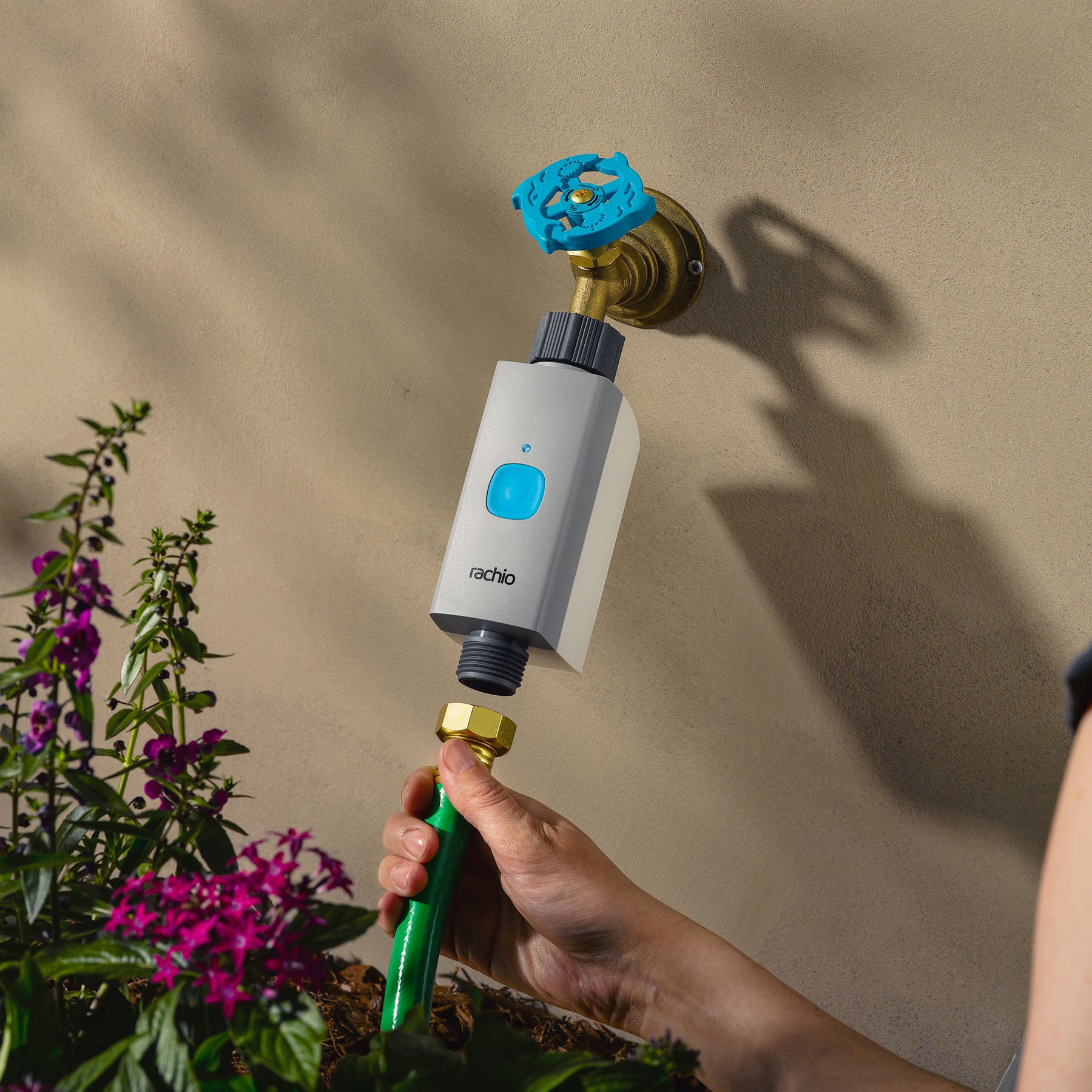 Woman attaching hose to Rachio Smart Hose Timer valve on outdoor spigot.